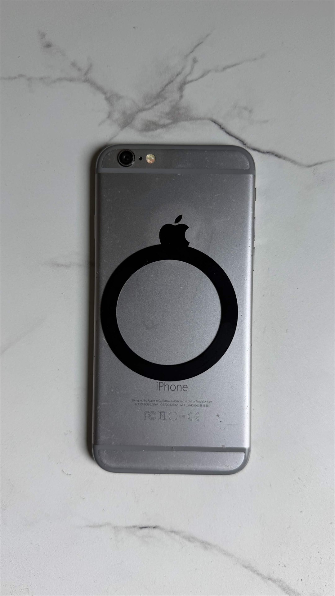 Black MagSafe adapter ring attached to the back of an older iPhone